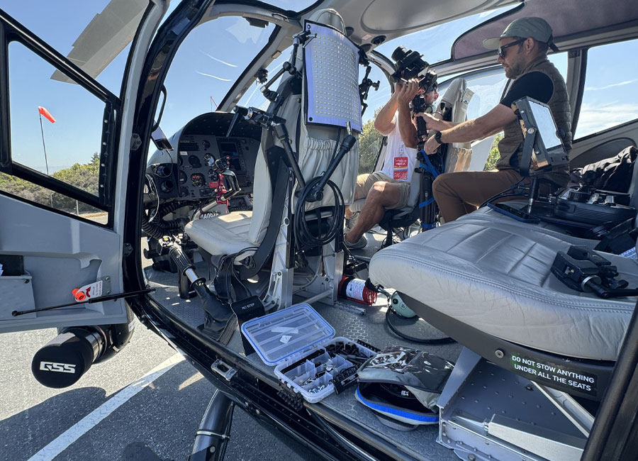 Film crew setting up camera and lighting equipment inside a Maverick helicopter, for live aerial TV broascasting, and GSS camera mount.