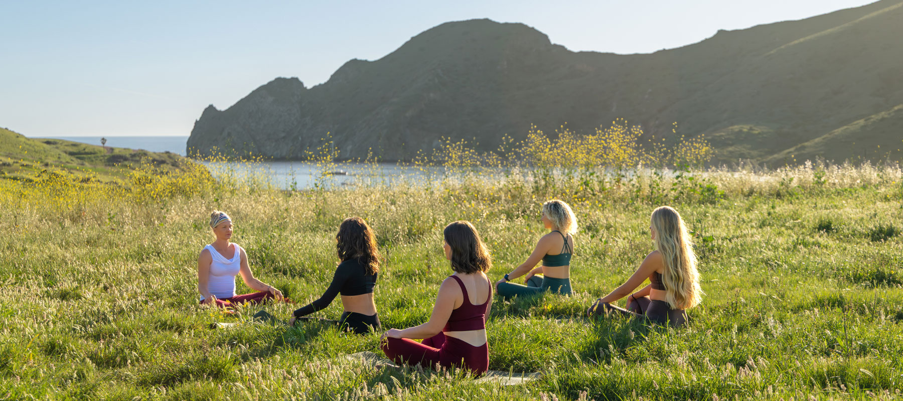 Guests meditating in a grassy meadow above the water at Two Harbors on Catalina Island