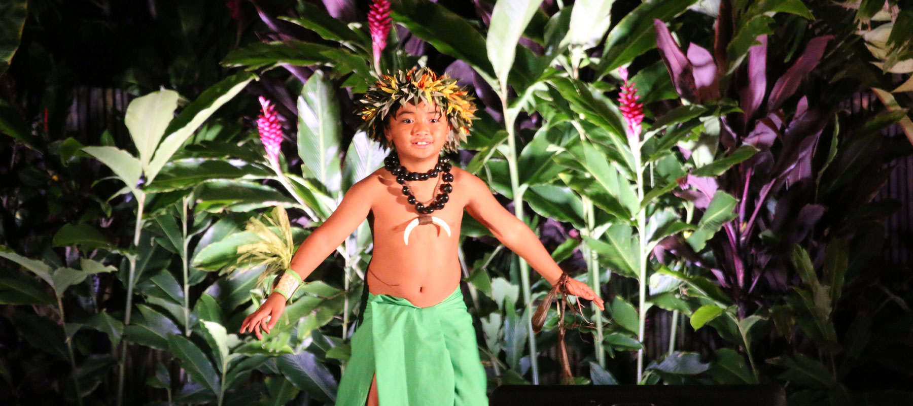 Polynesian male dancer in traditional headdress and attire at the Maui Luau Experience
