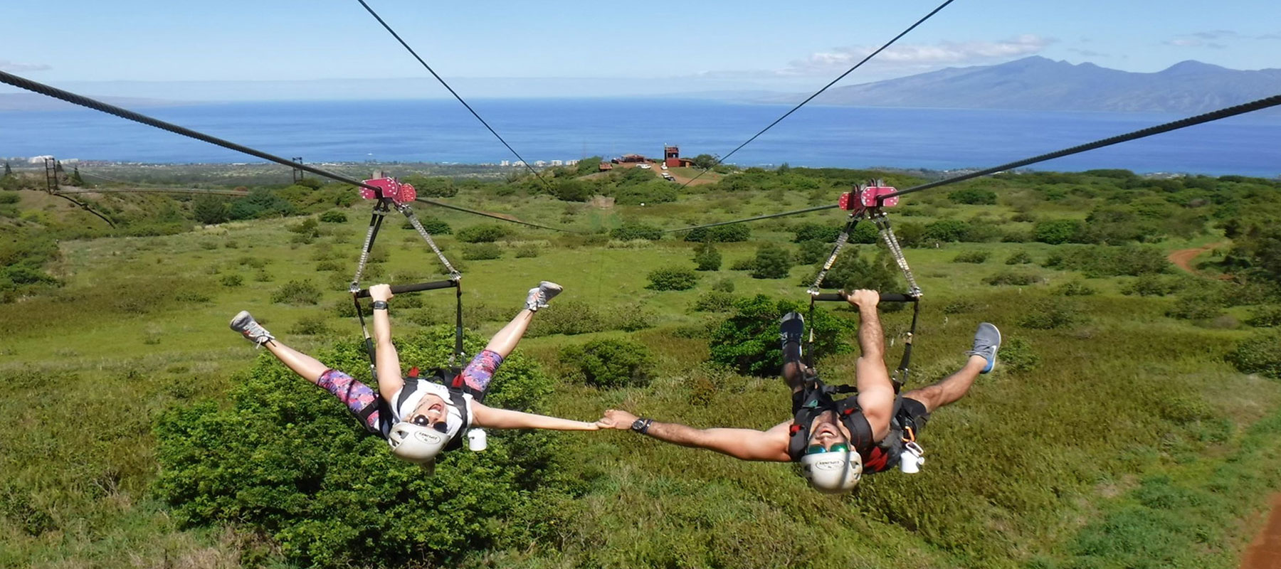 Smiling guest ziplining through lush greenery on private Maui zipline and helicopter adventure