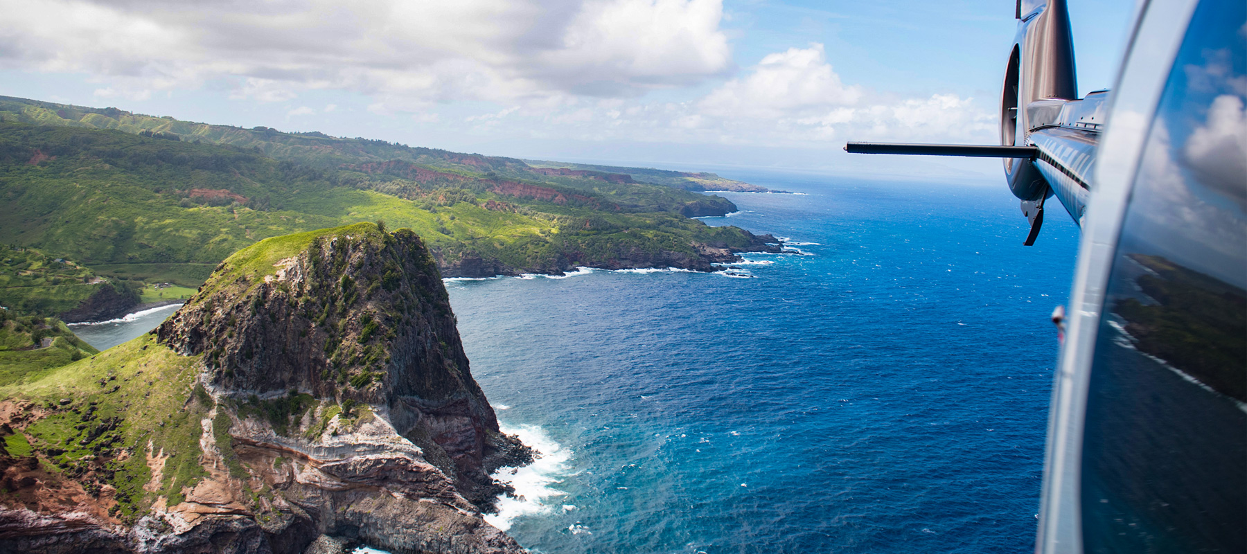 Rear view of a helicopter following the Maui coastline